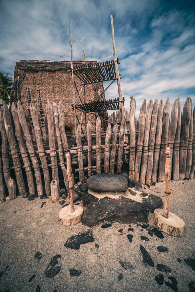 Puʻuhonua o Hōnaunau National Historical Park, Hōnaunau, Hawai'i (photo August 21, 2021): Hale o Keawe (thatched mortuary temple built by or for ruler Keawe-i-kekahi-aliʻi-o-ka-moku c.1700, last restored 2004) with recreated ki'i (divinity statues) and lele (a wooden offering tower or sacrificial altar).