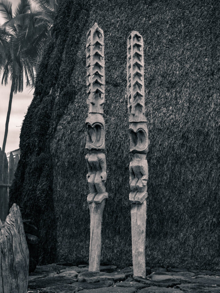 Puʻuhonua o Hōnaunau National Historical Park, Hōnaunau, Hawai'i (photo August 21, 2021): recreated ki'i (divinity statues) against Hale o Keawe (thatched mortuary temple built by or for ruler Keawe-i-kekahi-aliʻi-o-ka-moku c.1700, last restored 2004).