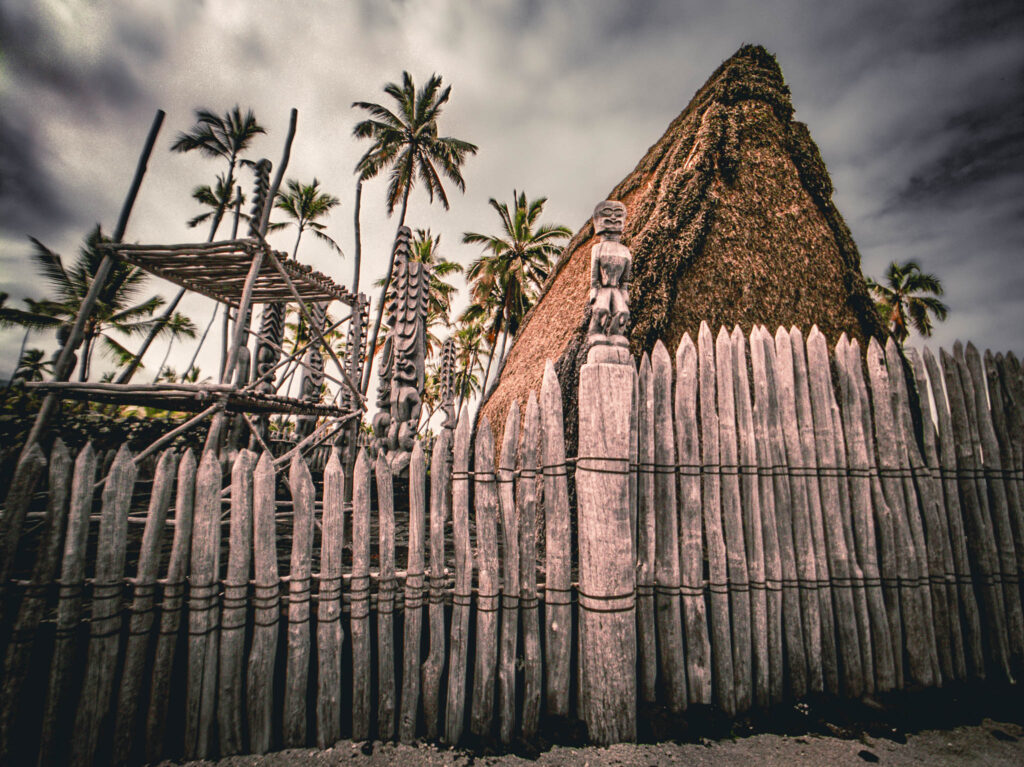 Puʻuhonua o Hōnaunau National Historical Park, Hōnaunau, Hawai'i (photo August 21, 2021): Hale o Keawe (thatched mortuary temple built by or for ruler Keawe-i-kekahi-aliʻi-o-ka-moku c.1700, last restored 2004) with recreated ki'i (divinity statues) and lele (a wooden offering tower or sacrificial altar).