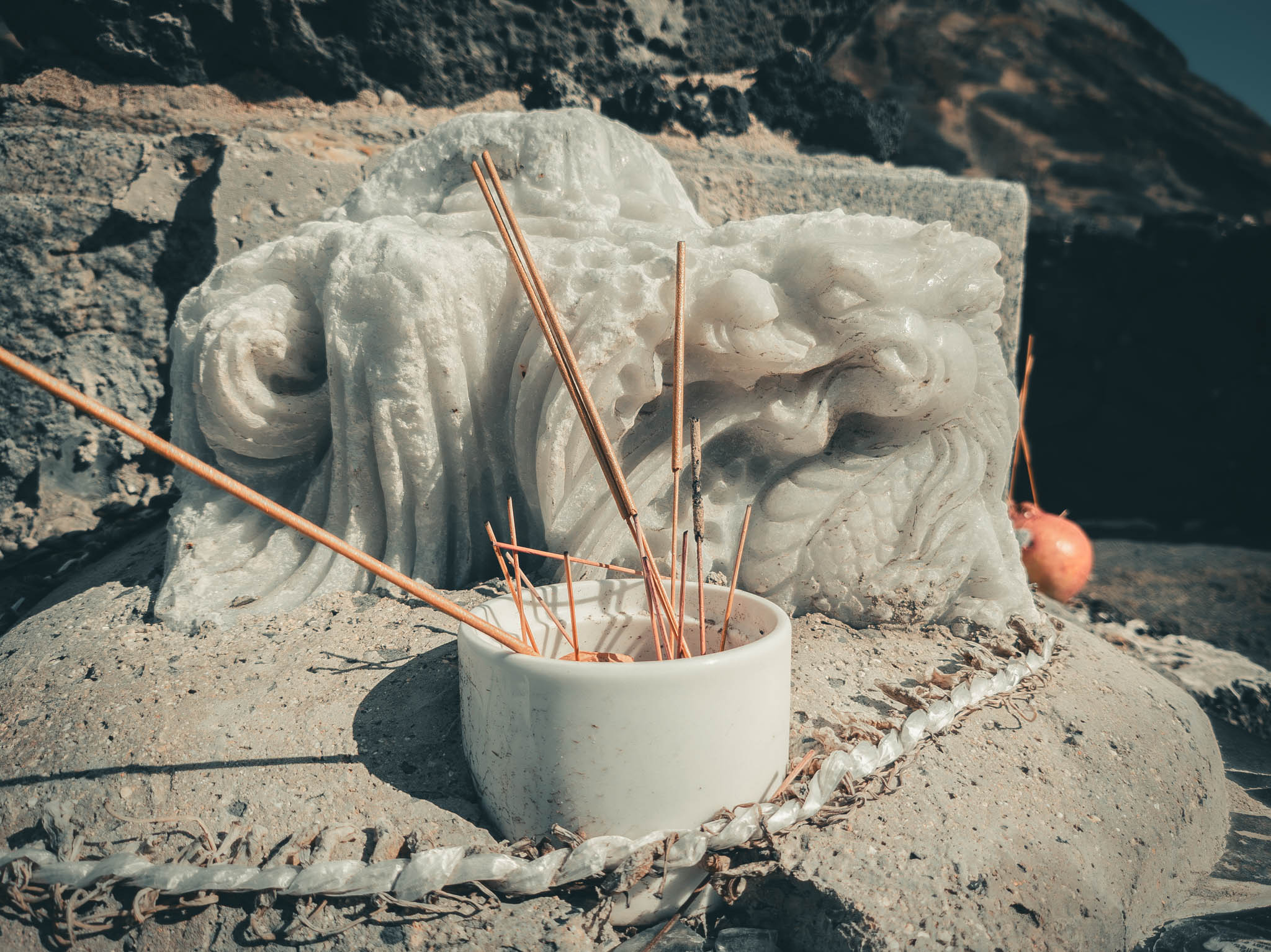 Japanese Fishing Shrine, Kalanianaʻole Highway, Oahu Island (photo 15 August 2021): incense sticks and remaining base of vandalized marble sculpture of Vietnamese Buddhist deity Quan Am Nam Hai.